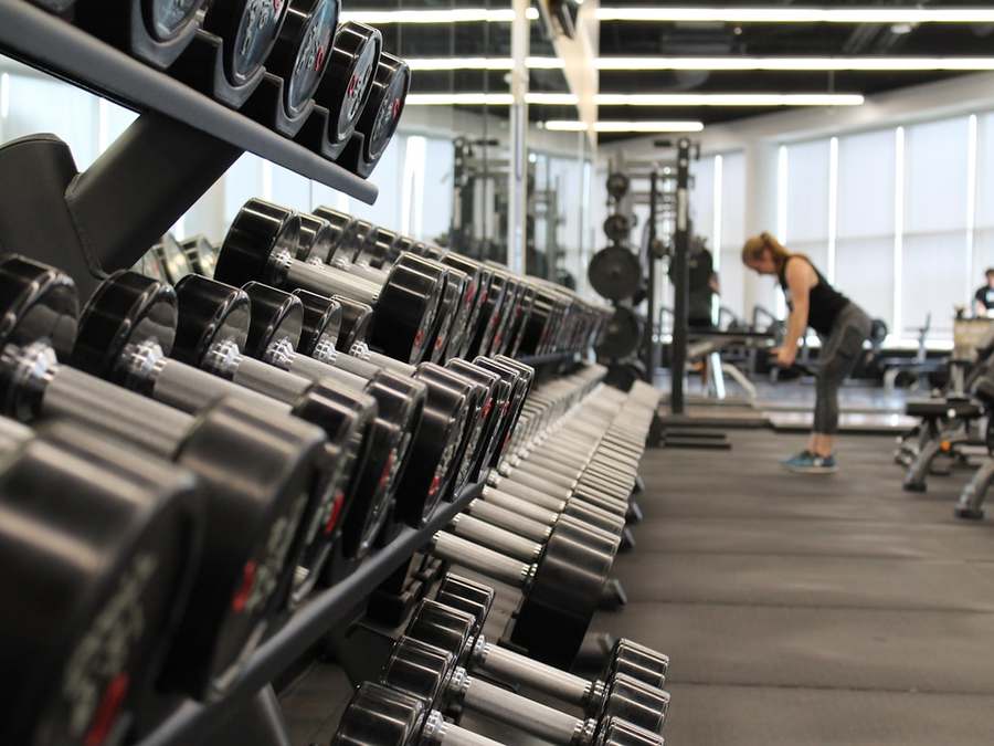A coach guiding a client through a lift in a gym